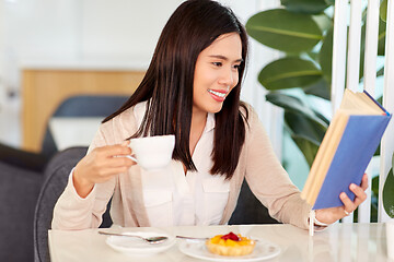Image showing woman drinking coffee and reading book at cafe