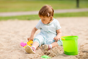 Image showing little baby girl plays with toys in sandbox