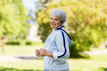 Image showing senior woman with earphones running in summer park