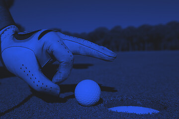 Image showing man\'s hand putting golf ball in hole