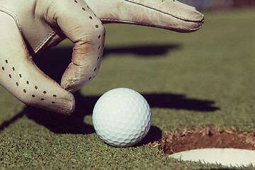 Image showing man\'s hand putting golf ball in hole