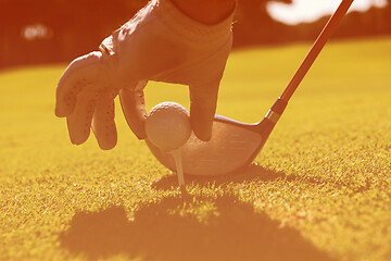 Image showing golf player placing ball on tee