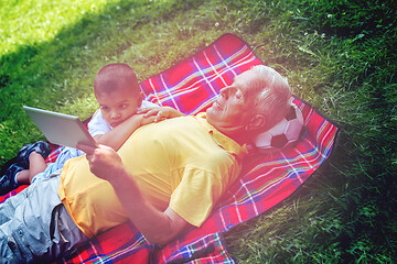 Image showing grandfather and child in park using tablet