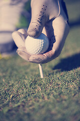 Image showing golf player placing ball on tee