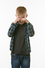 Image showing Crying boy rubs his eyes with his fists