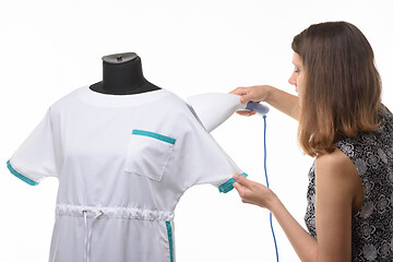 Image showing Girl seamstress steals a medical gown before issuing to a client