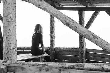 Image showing Girl alone sits early in the morning on a foggy day in a wooden arbor