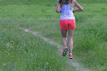 Image showing Young woman running in nature on a rural road 