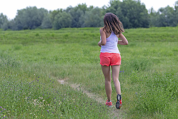 Image showing Young woman running in nature on a rural road 