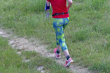 Image showing Young woman running in nature on a rural road 