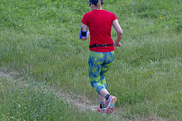 Image showing Young woman running in nature on a rural road 