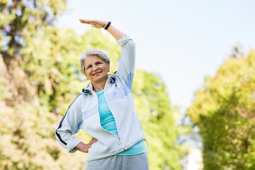 Image showing happy senior woman exercising at summer park