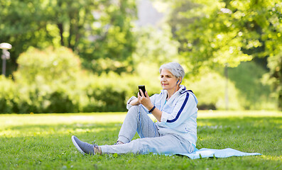 Image showing sporty senior woman with earphones and smartphone