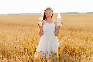 Image showing girl with bottle and glass of milk on cereal field