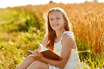 Image showing smiling girl reading diary on cereal field