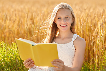 Image showing smiling young girl reading book on cereal field