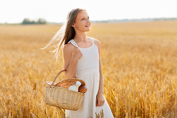 Image showing girl with bread and milk in basket on cereal field