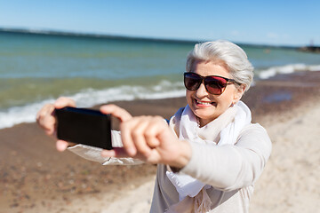 Image showing senior woman taking selfie by smartphone on beach