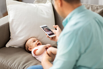 Image showing father with smartphone taking picture baby at home