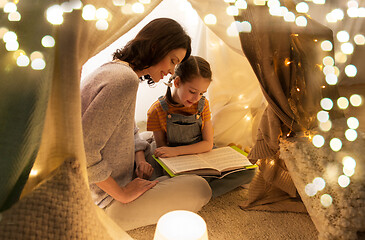 Image showing happy family reading book in kids tent at home