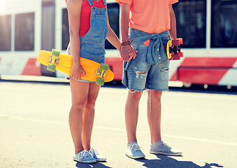 Image showing close up of young couple with skateboards in city