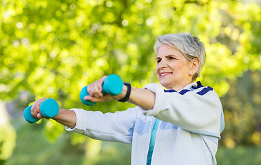 Image showing senior woman with dumbbells exercising at park