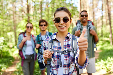 Image showing friends with backpacks showing thumbs up in forest