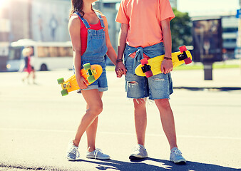 Image showing close up of young couple with skateboards in city