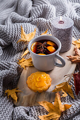 Image showing Cosy and soft winter background, with mulled wine, knitted blanket and candle with lemon cake on vintage wooden board. 