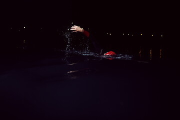 Image showing triathlon athlete swimming in dark night wearing wetsuit