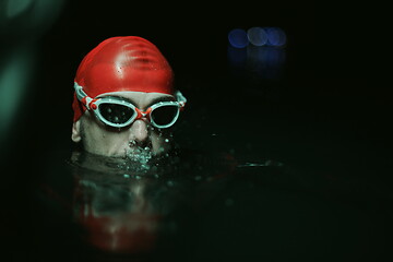 Image showing authentic triathlete swimmer having a break during hard training on night neon gel light
