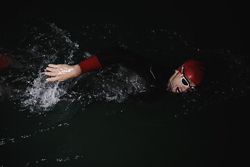 Image showing triathlon athlete swimming in dark night wearing wetsuit