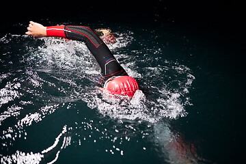 Image showing triathlon athlete swimming in dark night wearing wetsuit