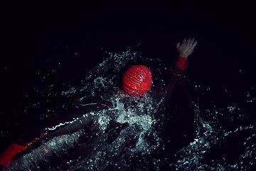 Image showing triathlon athlete swimming in dark night wearing wetsuit