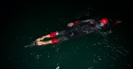 Image showing triathlon athlete swimming in dark night wearing wetsuit