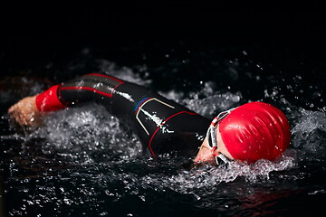 Image showing triathlon athlete swimming in dark night wearing wetsuit