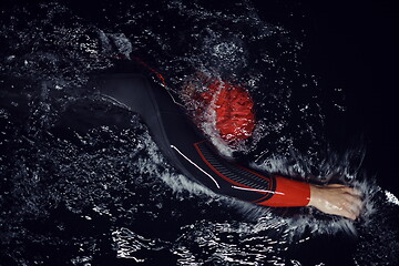 Image showing triathlon athlete swimming in dark night wearing wetsuit