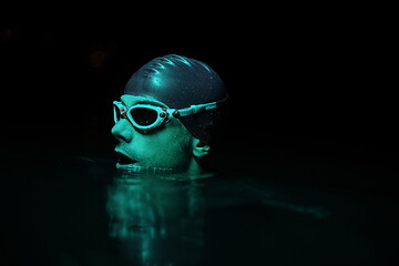 Image showing authentic triathlete swimmer having a break during hard training on night neon gel light