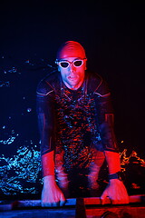 Image showing authentic triathlete swimmer having a break during hard training on night neon gel light