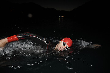 Image showing triathlon athlete swimming in dark night wearing wetsuit