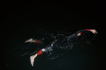 Image showing triathlon athlete swimming in dark night wearing wetsuit