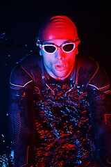 Image showing authentic triathlete swimmer having a break during hard training on night neon gel light