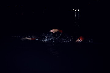 Image showing triathlon athlete swimming in dark night wearing wetsuit