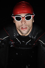 Image showing authentic triathlete swimmer having a break during hard training on night