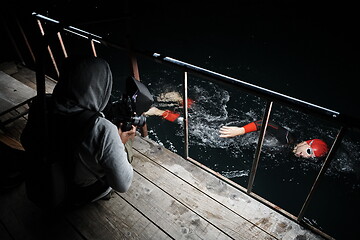 Image showing videographer taking action shot of triathlon swimming athlete at night