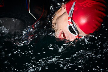 Image showing triathlon athlete swimming in dark night wearing wetsuit