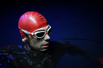 Image showing authentic triathlete swimmer having a break during hard training on night