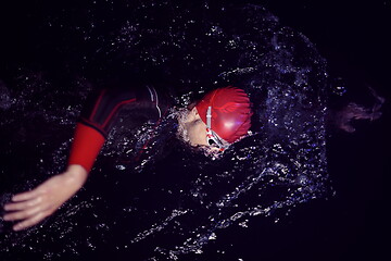 Image showing triathlon athlete swimming in dark night wearing wetsuit