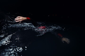 Image showing triathlon athlete swimming in dark night wearing wetsuit