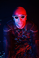 Image showing authentic triathlete swimmer having a break during hard training on night neon gel light